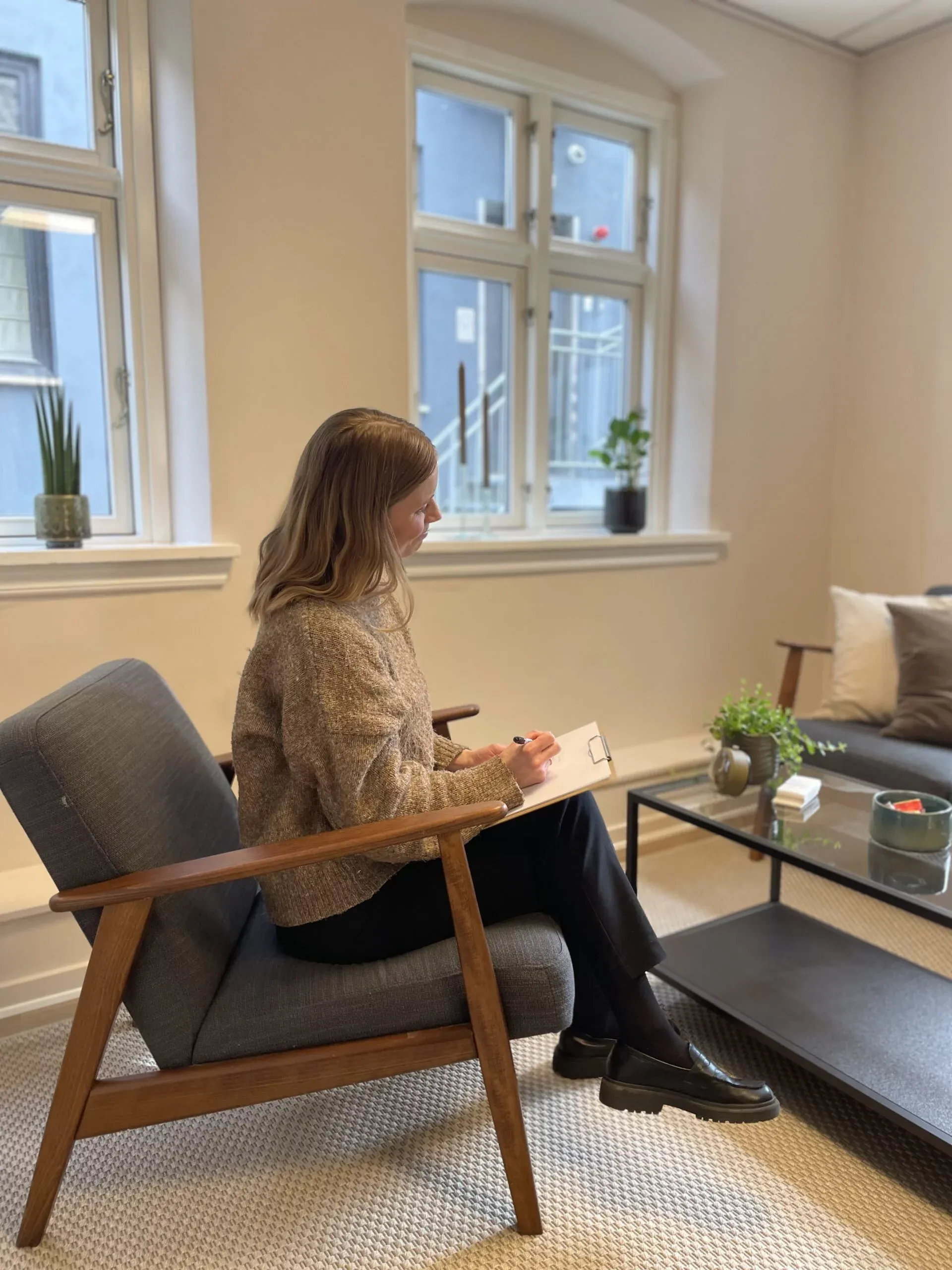 Kvinde sidder og skriver i notesblok i stue